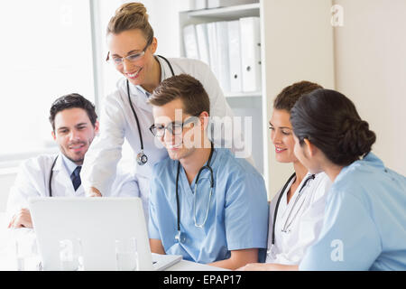 Smiling doctors and nurses discussing over laptop Stock Photo