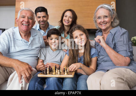 Portrait of happy extended family playing chess in living room Stock Photo