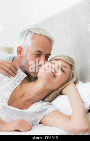 Mature man kissing womans cheek in bed Stock Photo