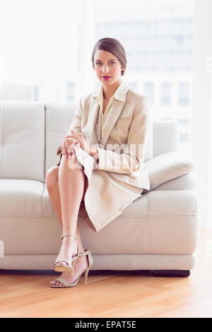 Thoughtful businesswoman sitting on sofa looking at camera Stock Photo