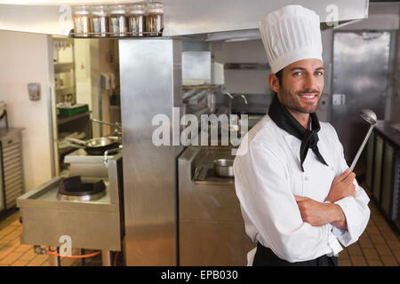 Happy chef looking at camera with arms crossed holding ladle Stock Photo