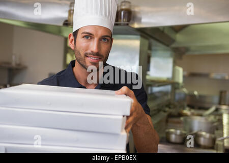 Happy pizza chef holding stack of pizza boxes Stock Photo
