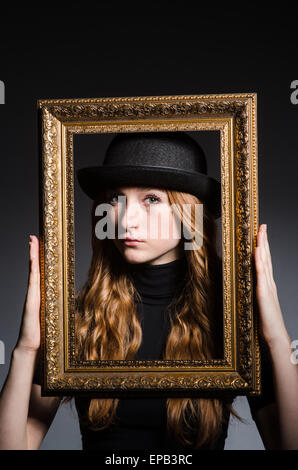 Redhead with picture frame against dark background Stock Photo