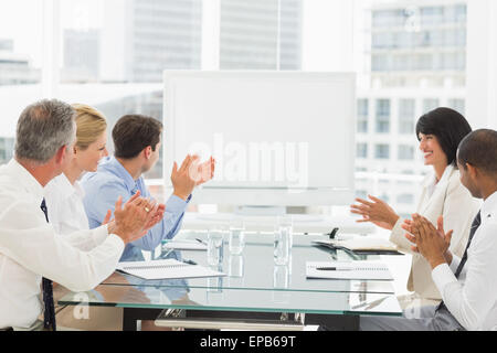 Business people clapping at blank whiteboard in conference room Stock Photo