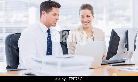 Smartly dressed colleagues using computer Stock Photo