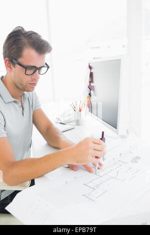 Concentrated man using compass on design Stock Photo