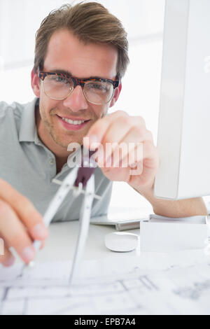 Smiling young man using compass on design Stock Photo