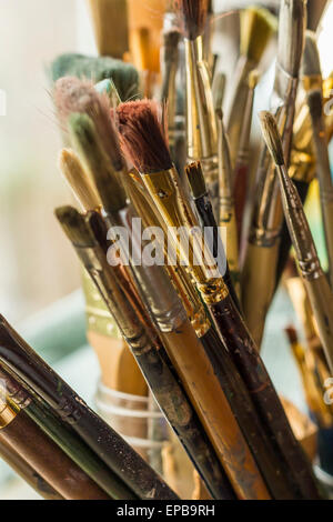 Container kit of assorted and stained old artist paintbrushes Stock Photo