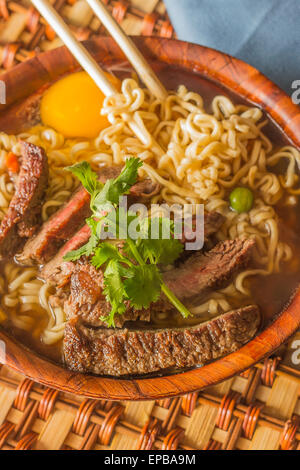 Beef ramen served Asian style. Raw egg cooks in steaming hot savory broth Stock Photo