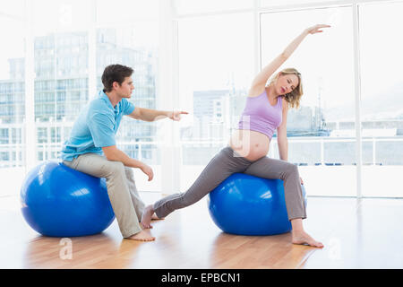Trainer exercising with blonde pregnant client on exercise balls Stock Photo