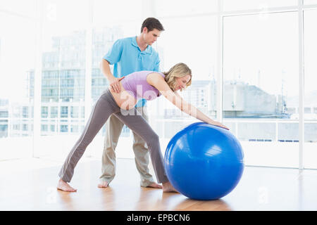 Trainer exercising with blonde pregnant client and exercise ball Stock Photo