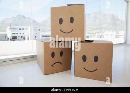 Three cardboard boxes with smiley signs against window Stock Photo