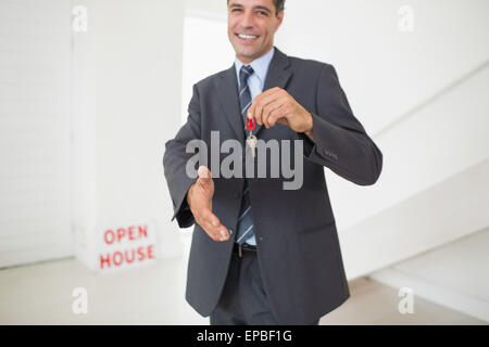 Businessman offering a handshake while holding up keys Stock Photo