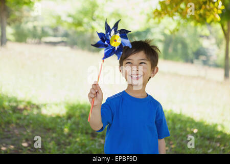 Happy cute little boy holding pinwheel at park Stock Photo