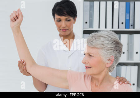 Physiotherapist assisting senior woman to stretch her hand Stock Photo