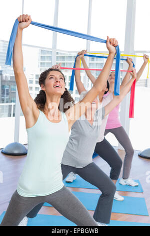 Class holding up exercise belts at yoga class Stock Photo