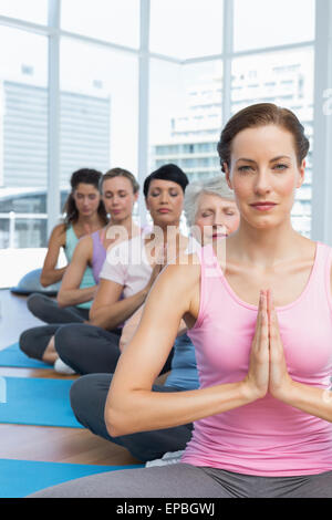 Class sitting with joined hands in a row at yoga class Stock Photo