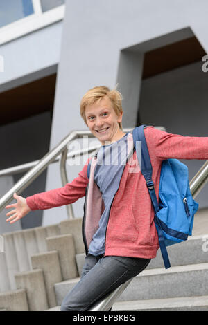 Excited student sliding down railing on stairway Stock Photo