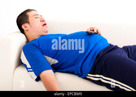 fat man sleep on the sofa and holding tv remote control Stock Photo