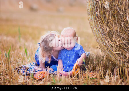 Two children, funny curly toddler girl and a little baby boy, wearing tradtional German costumes playing in a field Stock Photo