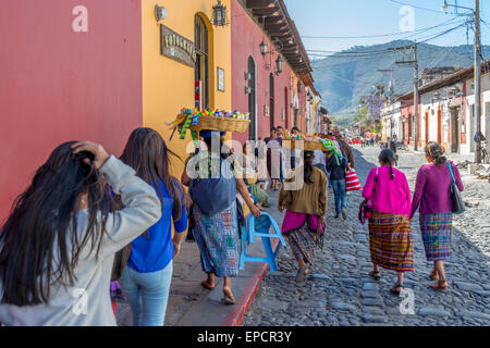 Women carrying baskets on their head while walking down the street in Antigua Guatemala Stock Photo