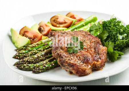 Glazed green asparagus with sesame seeds and grilled pork chop Stock Photo