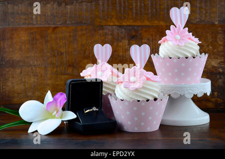 Wedding Day shabby chic style pink cupcakes on dark recycled vintage wood background. Stock Photo