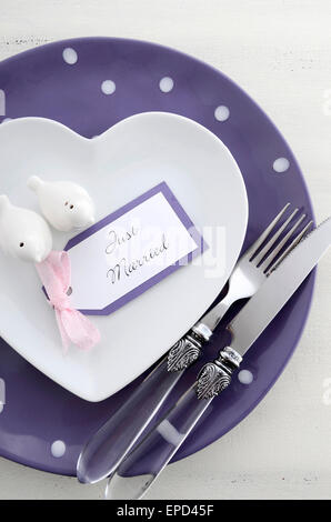 Purple theme wedding table place setting with heart shape plates and vintage silverware. Stock Photo