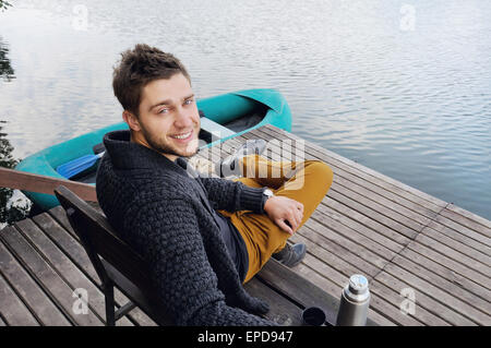 handsome attractive man on the wooden pier at the lake on beautiful nature background, relax concept Stock Photo