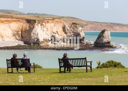 Women sitting on benches admiring the views at Freshwater Bay at Isle of Wight, Hampshire UK in May - seastacks sea stacks Stock Photo