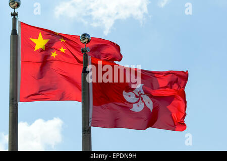 Hong Kong and Peoples Republic of China Flags Flying Side by Side Against Blue Sky Stock Photo