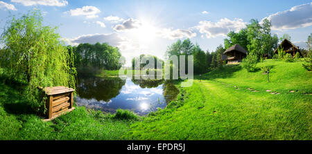 Wooden house near river at sunny day Stock Photo