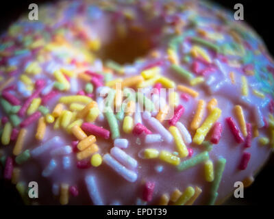 Closeup on a strawberry doughnut with pink icing and multi coloured sprinkles Stock Photo