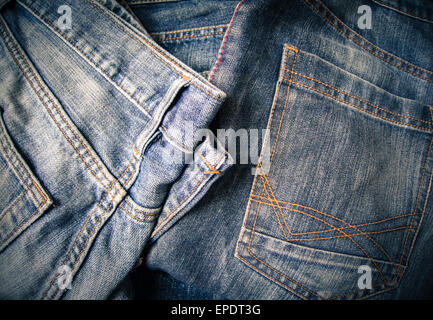 Old pairs of blue denim jeans with visible orange and red seams Stock Photo