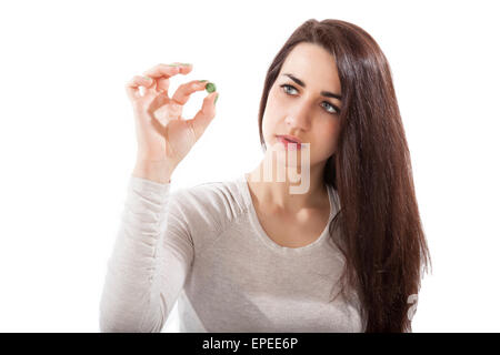 Beautiful girl in her 20s holding green chlorella and spirulina pill isolated on white background. Healthy eating, green Stock Photo