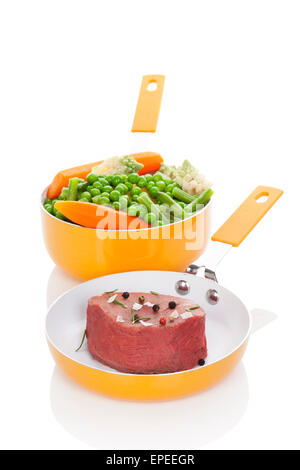 Big steak with steamed colorful vegetable in orange pan isolated on white background. Culinary delicious healthy meal. Stock Photo