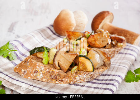 Delicious fresh bruschetta with seasonal vegetable and mushrooms on white wooden background. Culinary traditional eating. Stock Photo
