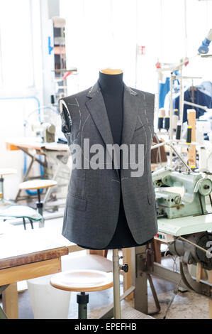 Working on a handmade jacket displayed on a mannequin ready for the fitting of the sleeves in the interior of a tailors shop Stock Photo