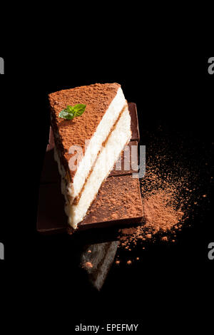 Tiramisu dessert on chocolate bar isolated on black background. Italian sweet dessert concept. Stock Photo