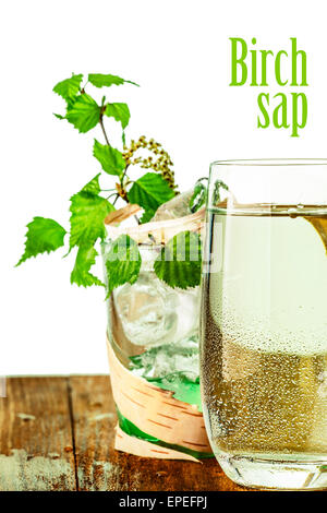 A glass of birch sap. Rural look. Birch juice in elegant highball standing on wooden table decorated with birch bark Stock Photo