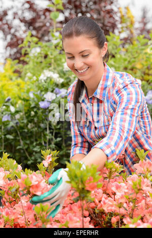 Garden center woman stands in flowerbed smiling Stock Photo