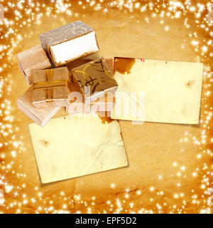 Gift box in gold wrapping paper on vintage cardboard background with glowing stars Stock Photo