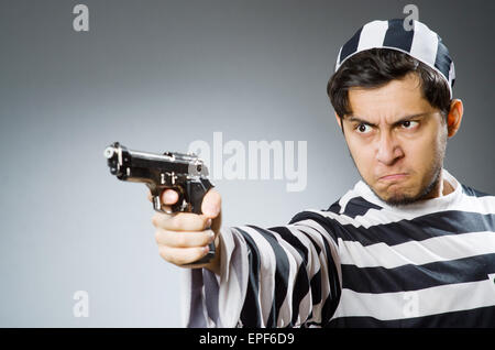 Prisoner with gun against dark background Stock Photo