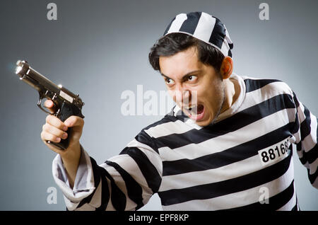 Prisoner with gun against dark background Stock Photo