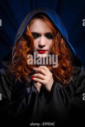 Young witch on blue rays background Stock Photo