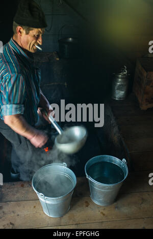 Szczawnica, Poland - May 9, 2015: Man working on traditional sheep milk cheese in smokehouse Stock Photo