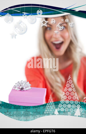 Composite image of astonished woman holding a gift Stock Photo