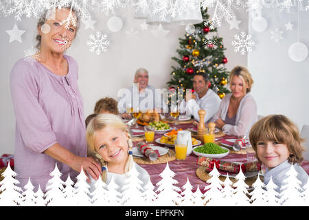 Composite image of grandmother and granddaughter standing beside the dinner table Stock Photo