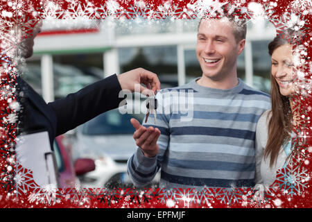 Composite image of couple receiving car keys by a dealer Stock Photo