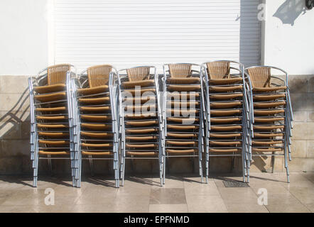 Chairs stacked outside restaurant in low season at seaside resort of Sitges, on the Costa Dorada, Catalonia, Spain Stock Photo